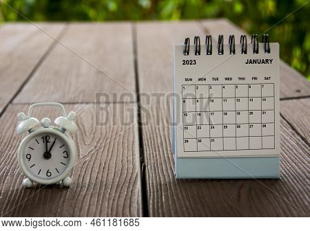 Alarm Clock Pointing At 1 O'clock With January 2023 Calendar On A Bench. Time And Calendar Concept.