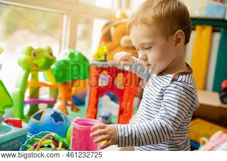Toddler Boy Plays With Toys In The Children's Room. Educational Toys For Young Children. Child One A