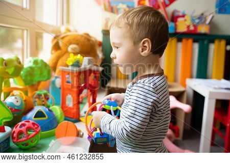 Toddler Boy Plays With Educational Toys In The Children's Room. The Study Of Colors And The Developm