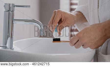 Close-up Of Male Hands In Bathrobe Holding Bamboo Wooden Dental Tally Squeezing Out Tube Of Whitenin