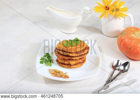 Delicious Russian Pancakes With Pumpkin And A Cup Of Sour Cream On A Bright Table, Selective Focus. 