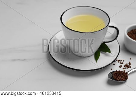 Cup Of Buckwheat Tea And Granules On White Marble Table, Space For Text