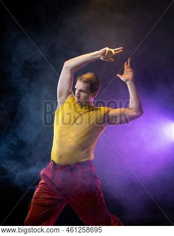 A Young Muscular Man In A Bright Outfit Poses In A Pretentious Pose, Style And Grotesque. Attractive