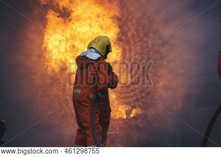 Firefighter Rescue Training In Fire Fighting Extinguisher. Firefighter Fighting With Flame Using Fir