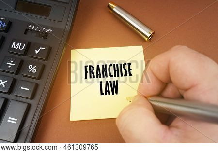 Business Concept. A Calculator Lies On A Brown Surface, A Hand With A Pen Makes An Inscription On A 