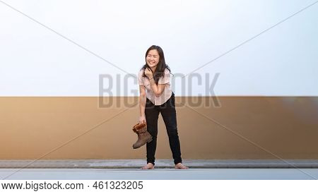 Asian Woman Holds Brown Boots In Her Hand And Posting For Photo Shooting At Rooftop Environment At T