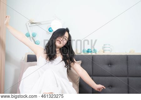 Asian Young Glasses Woman Stretches Oneself On Her Bed In The Morning.