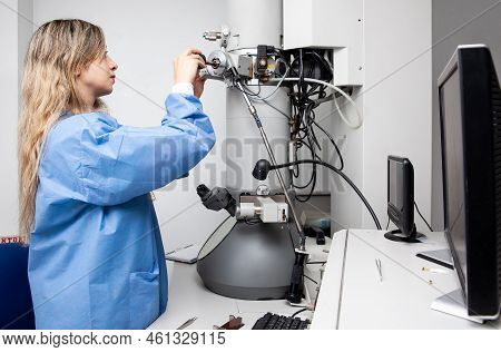Young Female Scientist Loading A Specimen Using A Sample Holder Into A Transmission Electron Microsc