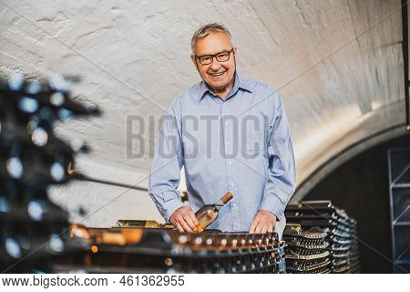 Portrait Of Senior Man Who Owns Winery. He Is Examining Quality In His Wine Cellar. Industry Wine Ma