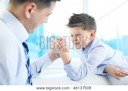 Photo du petit garçon et son papa armwrestling
