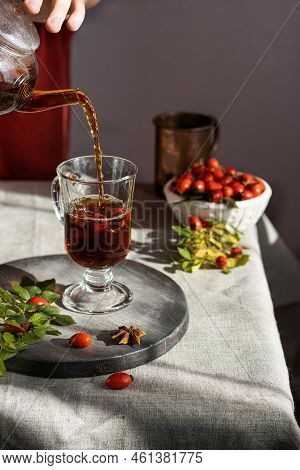 Female Hand Pours Hot Herbal Tea Into A Glass Mug. Vertical