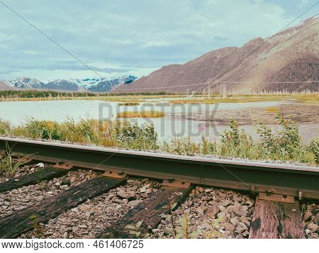 Expansive Wetland Landscape Of Water And Green Vegetation Stretching In Distance Bounded By Mountain