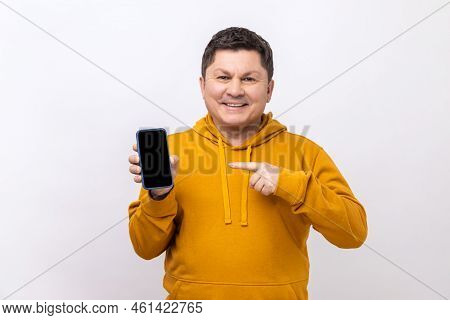 Middle Aged Man Pointing Finger At Smartphone With Empty Screen, Looking At Camera With Smile, Frees