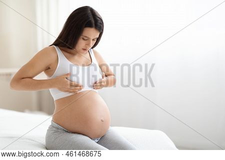 Pregnant Woman Sitting On Bed, Having Painful Feelings In Breast