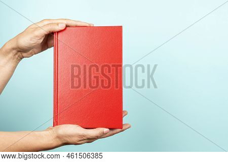 Woman Hands Holding Book With Blank Red Cover Over Light Blue Background. Education, Back To School,