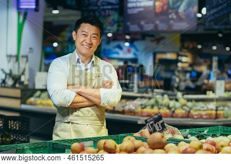 Portrait Of A Happy Handsome Asian Salesman. Vegetables And Fruits At The Market Or Grocery Store. S