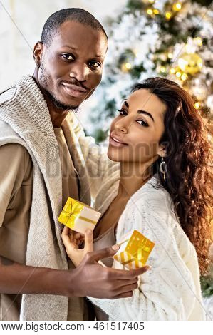 A Happy Couple Of Mulattoes Exchange Gifts With Each Other. Celebrating Joint Family Events.