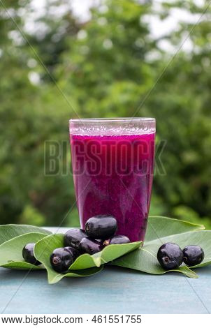 Closeup Of Jamun Or Black Plum Juice In A Glass With Fruit And Leaves Isolated On Wooden Background 