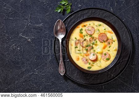 Kartoffelsuppe, German Potato Soup With Sausages In Black Bowl On Dark Concrete Table, Horizontal Vi