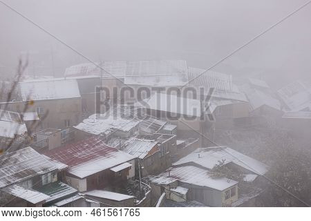 Panoramic View Of Gunib Village In Dagestan, Russia. Private Houses In The Fog. Snow-covered Roofs O