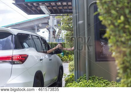 Hand Man In Car Receiving Coffee In Drive Thru Fast Food Restaurant. Staff Serving Takeaway Order Fo