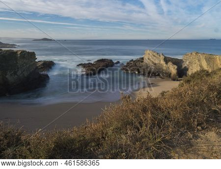 View Of Empty Praia Dos Buizinhos Sand Beach With Long Exposure Blurred Ocean Waves And Sharp Rock A