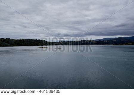 Sea Of Gray Tones Under A Cloudy Sky With Mountains In The Background. Copyspace. Horizontal Photogr