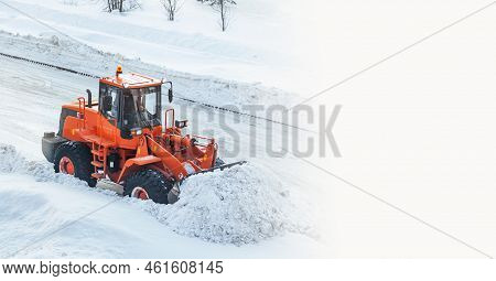 A Large Orange Tractor Removes Snow From The Road And Clears The Sidewalk. Cleaning And Clearing Roa