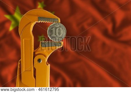 Kyrgyzstani Ten Som Coin Clamped In An Orange Plumber Wrench On The Background Of The Flag Of China.