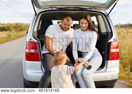 Image Of Happy Family Traveling Together By Their Comfortable Car, Stop To Heve Rest And Drinking Te
