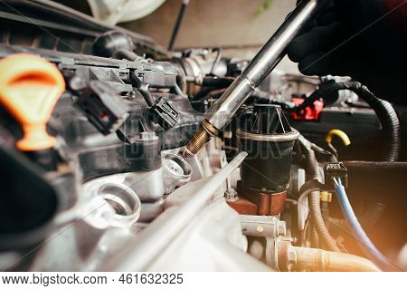 A Auto Mechanic Is Installing Automobile Iridium Spark Plugs Into The Ignition Spark Socket Of The E
