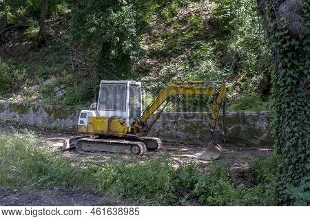 Excavator Single-bucket  For For Earthworks In The Mountains, Is Parked On A Path In A Forest Area O