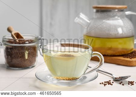 Cup Of Buckwheat Tea, Hot Teapot And Granules On White Wooden Table