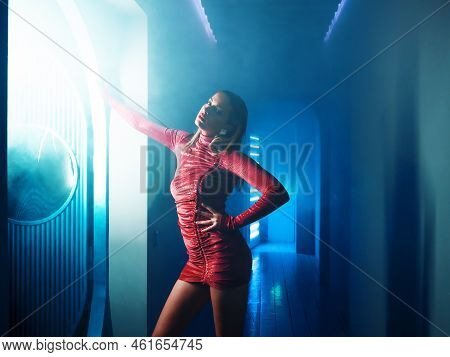 A Fashionable Photo Shoot With Tinted Blue, A Young Beautiful Model In A Scarlet Dress, In A Mysteri