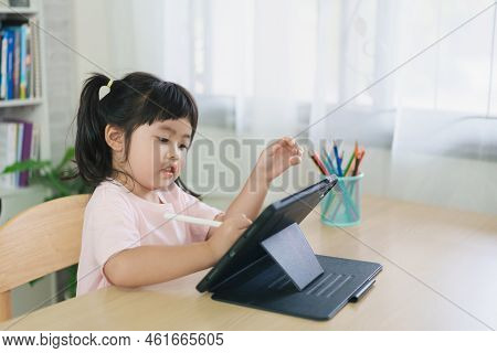 Asian Girl Looking And Touch On White Screen At The Tablet Screen Attentively. Overstimulated Childr