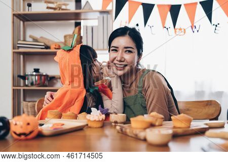 Young Girl And Mother At Halloween Making Treats And Cupcake On Table. Happy Halloween Day