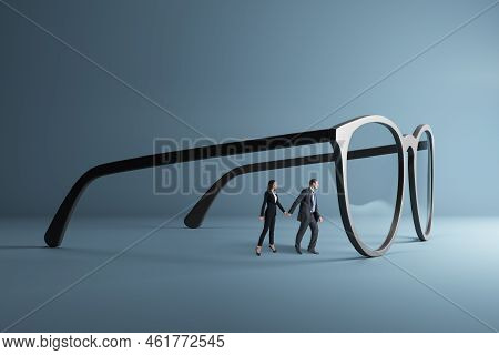 Thoughtful Young Businessman And Woman Holding Hands And Looking Through Abstract Huge Glasses On Gr