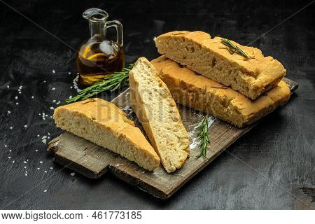 Homemade Italian Focaccia Modenese, With Rosemary And Olive Oil On A Wooden Board. Food Recipe Backg