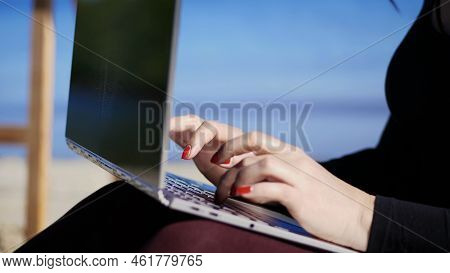 Summer, Sea Beach. Close-up Of Female Hands With Bright Red Manicure, Type On The Laptop Keyboard. W