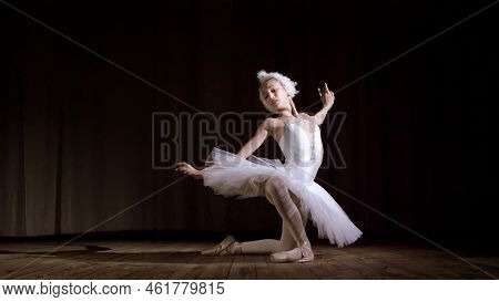 In Rays Of Spotlight, On The Stage Of The Old Theater Hall. Young Ballerina In Suit Of White Swan An