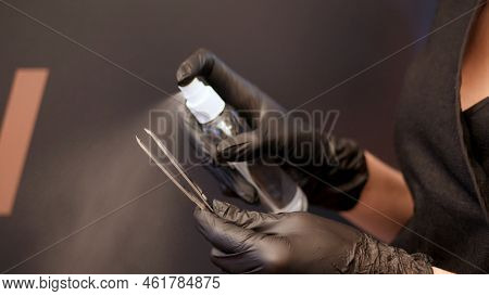 Beauty Saloon. Close-up, The Hands Of The Beautician In Black Rubber Gloves Hold Tweezers For Eyebro