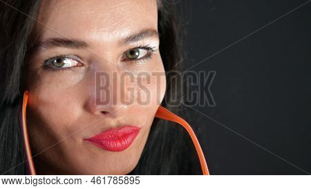 Portrait Of A Sexy Brunette Woman With Red Lips Who Eroticly And Playfully Tries On Stylish Glasses,