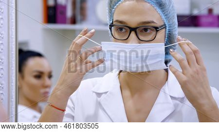 Cosmetology Room In The Clinic, A Female Doctor Wearing Glasses, Wearing A White Uniform, Dresses A 