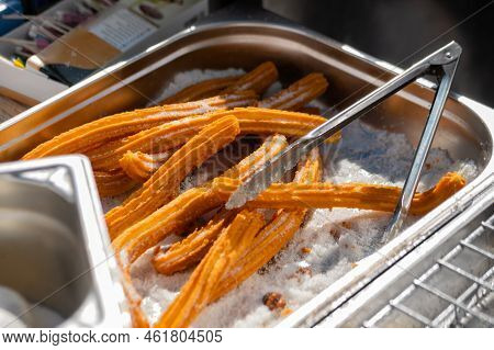 Homemade Crunchy Churros With Powdered Sugar And Cooking Tongs At Summer Outdoor Food Market - Close