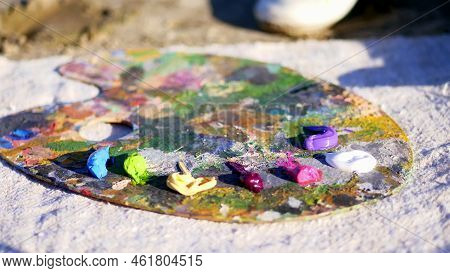 Close-up, Female Hands With Bright Red Manicure. Art Palette. The Artist Squeezes Some Purple Paint 