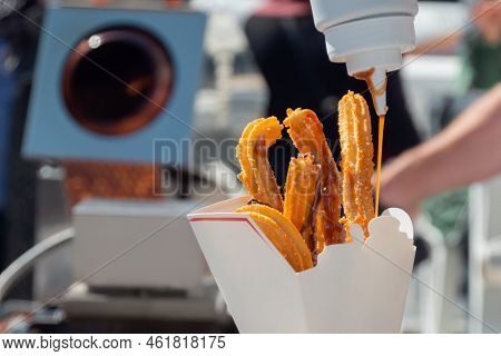 Chef Woman Pouring Caramel Sauce On Homemade Crunchy Churros In Paper Box At Summer Outdoor Food Mar