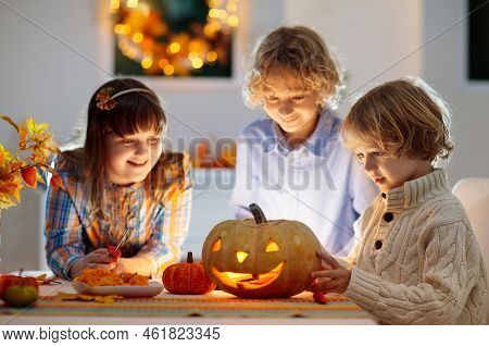 Family Carving Pumpkin For Halloween Celebration. Boy And Girl Child Cutting Jack O Lantern For Trad