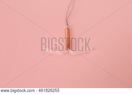 Copper Intrauterine Contraceptive Device On Light Pink Background