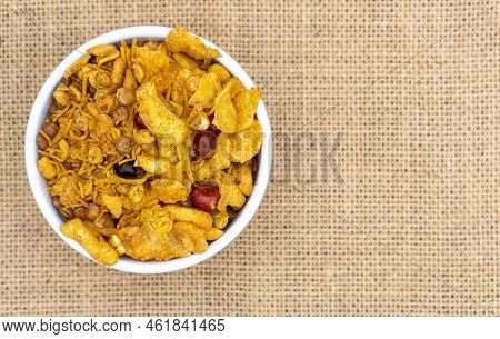 Top View Of Spicy Chanachur In White Bowl Isolated On Burlap Fabric Background With Copy Space, Morn
