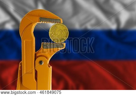 20 Euro Cent Coin Clamped In An Orange Plumber Wrench On The Background Of The Russian Flag. Reverse